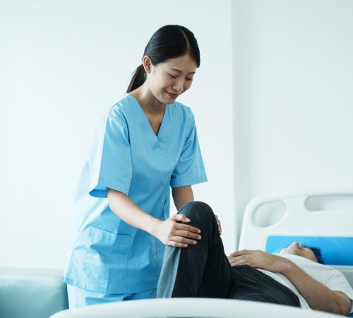 Therapist doing leg stretching exercises with senior patient in the clinic.